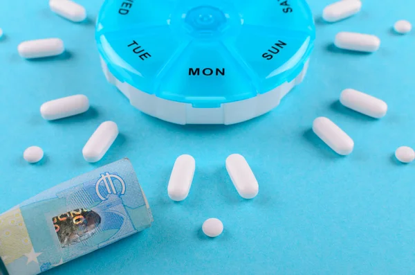Ліки з коробкою таблеток і євро гроші на синьому фоні — стокове фото