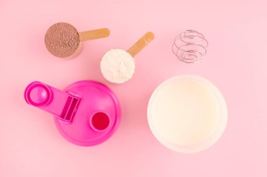 Çalkalayıcılı protein ve pembe arka planda taze süt.