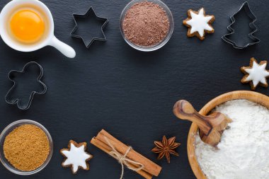 Siyah zemin üzerinde malzemeler ve kurabiye kesicisi, düz yatıyordu