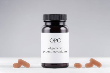 Gri arka planda besin takviyesi opc üzüm tohumu özü şişesi ve kapsüller