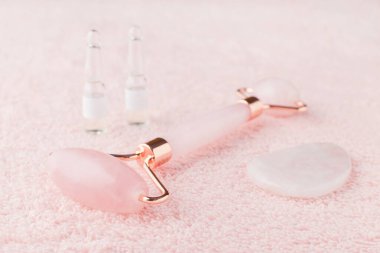 Gerçek gül kuvars yüz silindiri, gua sha masaj taşı ve ampullerde yüz serumu, seçici odaklanma