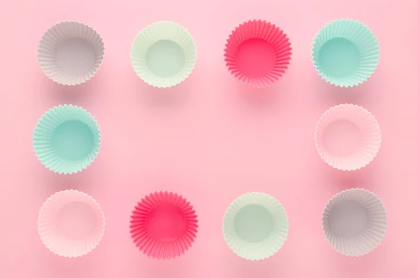 Silikonové formy pro pečení muffinů a cupcakes na pastelově růžovém pozadí — Stock fotografie