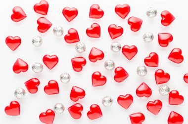 Beyaz arka plan, kırmızı kalpler desenli ve gümüş takılar, düz yatıyordu.