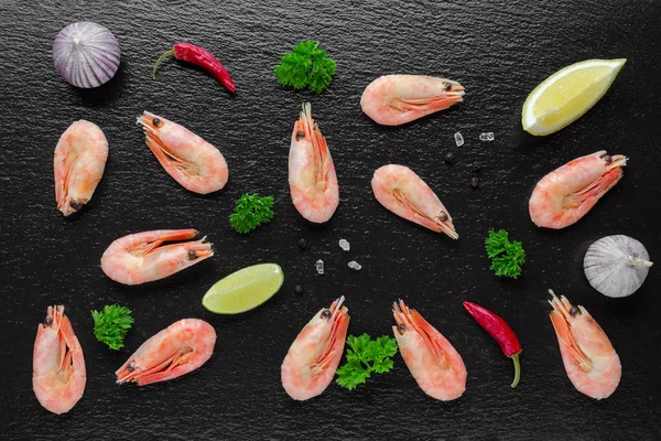 food background with cooked shrimps, chili, garlic and lemon on black background