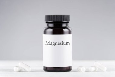 Gri üzerine besin takviyesi magnezyum şişe ve kapsüller