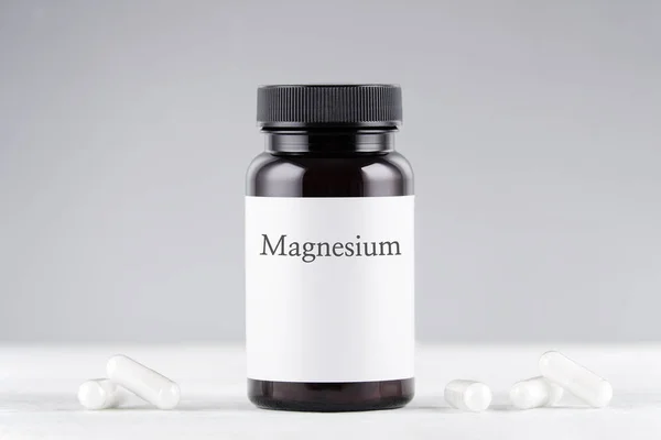 Voedingssupplement magnesium fles en capsules op grijs Stockfoto