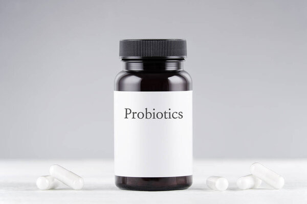 nutritional supplement probiotics bottle and capsules on gray
