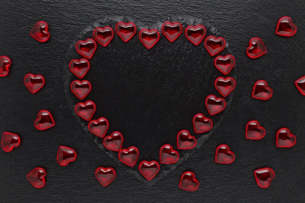 Zwarte leisteen plaat met rode harten op zwarte achtergrond Rechtenvrije Stockafbeeldingen
