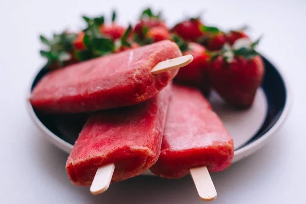 Delicious ice cream sticks with strawberries on a white background