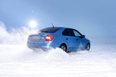 Vorkuta, Komi / Rusya - 12 01 2018: Kışın kar altında farları açık halde Skoda Rapid mavi araba. Kar fırtınasında dinamik hareket ve arabanın geri dönüşü.