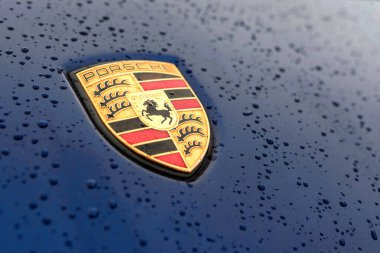 Vorkuta, Komi / Russia - 03 11 2017: Porsche car emblem on the bonnet of the blue color with drops clipart