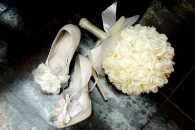 Siyah arka planda düğün buketi olan beyaz süslü nedime ayakkabıları. Ziyafetin sonu, yorgun gelin.