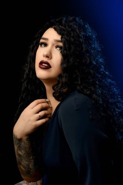 Koyu renk elbiseli güzel esmer bir kızın portresi mavi fosforlu siyah bir arka planda.