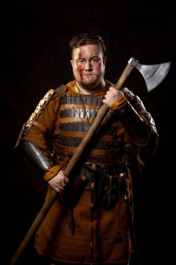 İskandinav bir savaşçı deri ve metal zırhlı, arka planda savaş baltası olan bir Viking. Kan ve kesik yara.