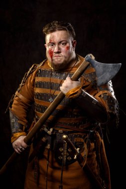 İskandinav bir savaşçı deri ve metal zırhlı, arka planda savaş baltası olan bir Viking. Kan ve kesik yara.