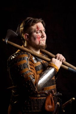 İskandinav bir savaşçı deri ve metal zırhlı, arka planda savaş baltası olan bir Viking. Kan ve kesik yara.