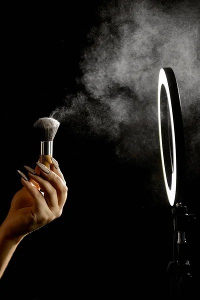 化妆艺术家的手用化妆品刷在环灯前的深色背景下 — 图库照片