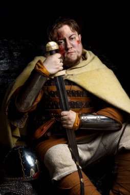 İskandinav bir savaşçı deri ve metal zırhlı, arka planda savaş baltası olan bir Viking. Kan ve kesik yara.