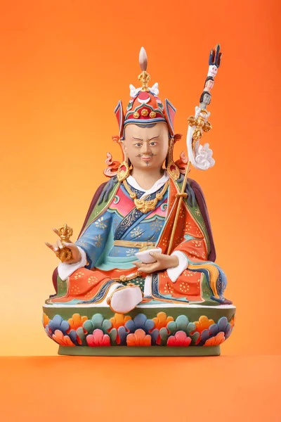 Beeldje van Padmasambhava op een oranje achtergrond. — Stockfoto