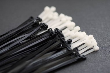 Gri bir arka plan üzerinde siyah ve beyaz plastik bağları.