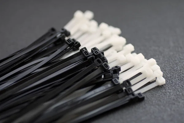 Gri bir arka plan üzerinde siyah ve beyaz plastik bağları.