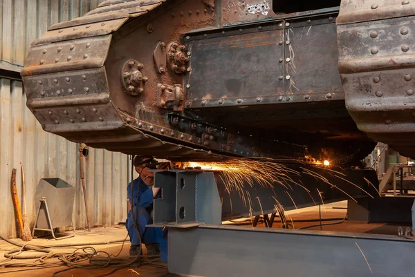 Un lavoratore esegue lavori di rettifica su una vecchia cisterna blindata in un facto Immagine Stock