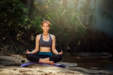 Yoga uygulamak ve ormanda rahatlatıcı yoga arka genç kadın