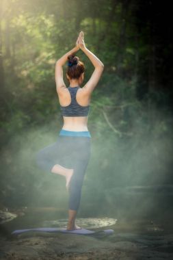 Yoga uygulamak ve rahatlatıcı yoga arka genç kadın