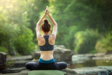 Yoga uygulamak ve şelale rahatlatıcı yoga genç kadın 