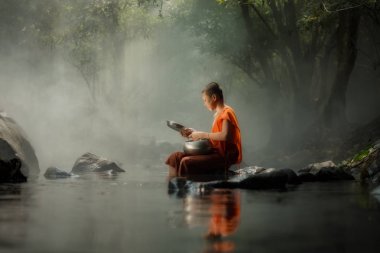 Tayland dere veya ormandaki nehir üzerinde oturan küçük keşiş 