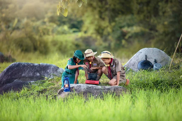 Les scouts trois cuisinent dans un camp ou un champ — Photo