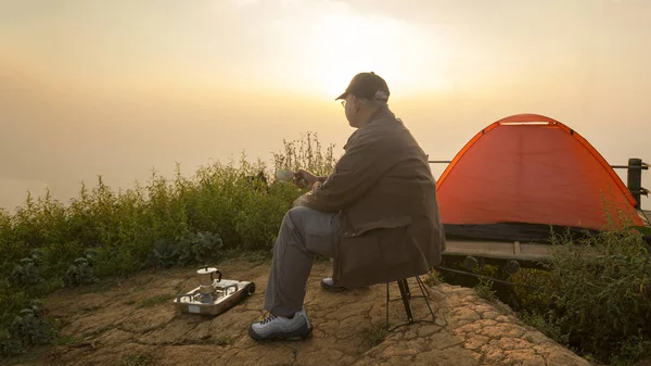 Старший кемпер сидя пить кофе в утреннее время смотреть восход солнца — стоковое фото