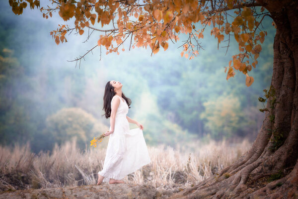 Young Beautiful woman wearing white dress enjoying with tree of nature.
