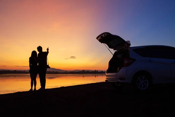 The couple standing in the silhouetted sunset and a car — Stock fotografie