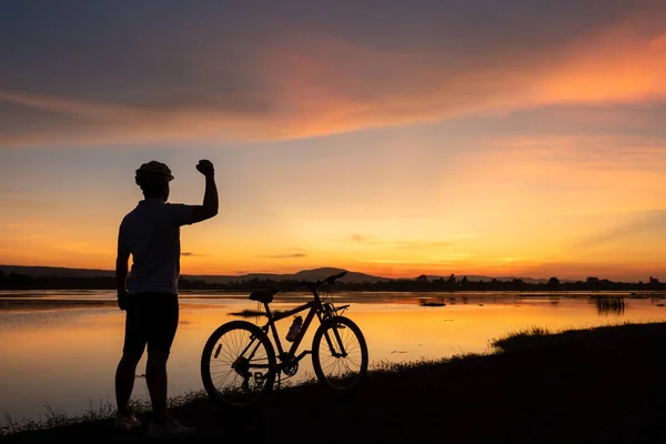 Männer radeln Fahrrad Erfolg auf der Straße in der Sonnenuntergangszeit — Stockfoto