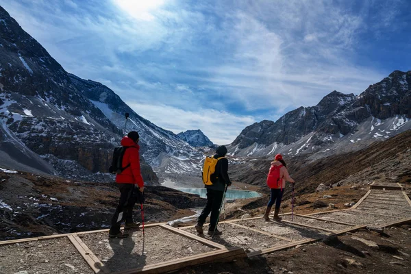 Three tourists walking trekking up the iceberg in China\'s Yading