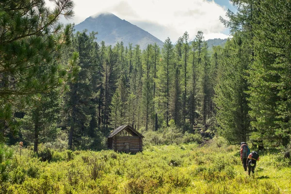 Дерев'яна хата в гори Алтай і пара туристів — стокове фото