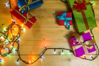 Ahşap arka plan tebrik kartı tatil kavramı mevcut kutulara. Ahşap masa üzerinde Noel renkli hediye kutuları. Üstten Görünüm kopya alanı ile. Noel Romantik ışıklar çerçeve ahşap arka plan üzerinde.