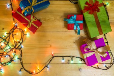 Ahşap arka plan tebrik kartı tatil kavramı mevcut kutulara. Ahşap masa üzerinde Noel renkli hediye kutuları. Üstten Görünüm kopya alanı ile. Noel Romantik ışıklar çerçeve ahşap arka plan üzerinde.