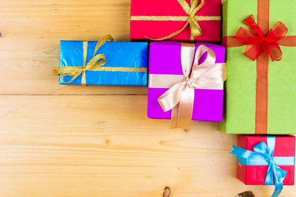 Presente cajas en el concepto de vacaciones de tarjetas de felicitación de fondo de madera. Navidad coloridas cajas de regalo en la mesa de madera. Vista superior con espacio de copia —  Fotos de Stock