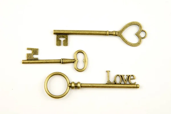 Ornamental medieval vintage keys with intricate forging, composed of fleur-de-lis elements, victorian leaf scrolls and heart shaped swirls. antique golden door key isolated on white background — Stock Photo, Image