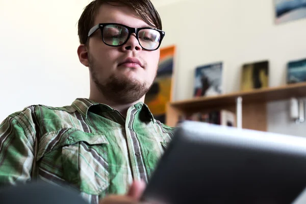 Portrét mladé muže pomocí tabletového počítače v domácí interiér — Stock fotografie