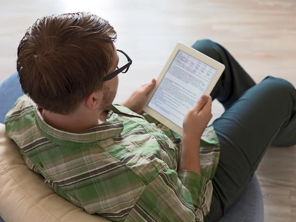 Young Man met behulp van Tablet PC met houten vloer achtergrond — Stockfoto