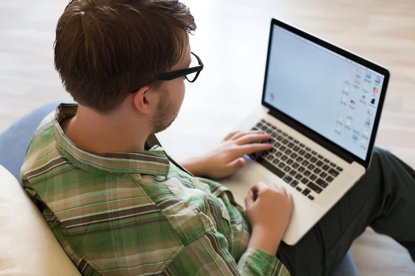 Junger Mann benutzt tragbaren Computer mit Holzboden-Hintergrund — Stockfoto