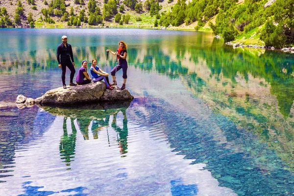 Group of smiling Hikers on rock at Mountain Lake — Stock fotografie