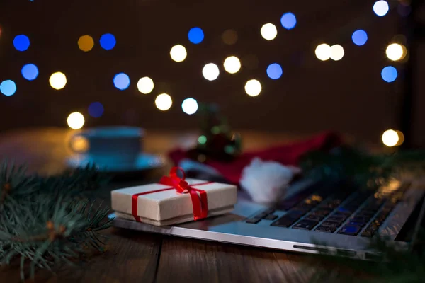 Laptop ve ahşap masa Noel ışıkları ile hediye kutusu — Stok fotoğraf