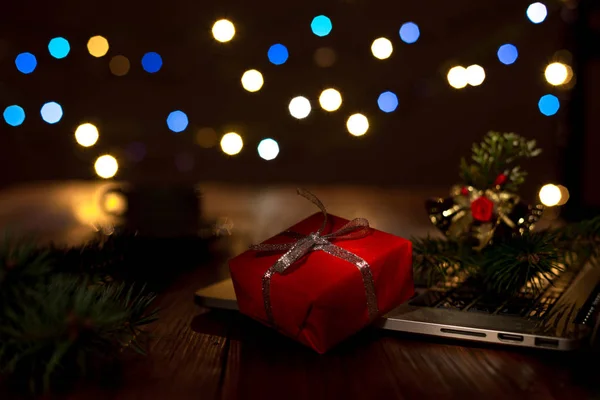 Greetings throw Internet Gift Box Computer and Christmas Lights dark — Stock Photo, Image