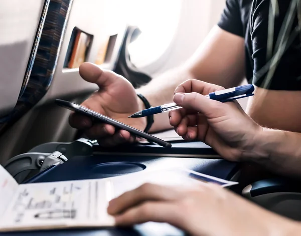 Handen van vlucht passagiers invullen van formulieren van de immigratie in vliegtuigen — Stockfoto