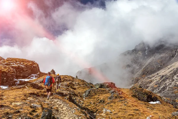 Fjällvandrare gå på gräsbevuxen terräng vackra moln och sol — Stockfoto