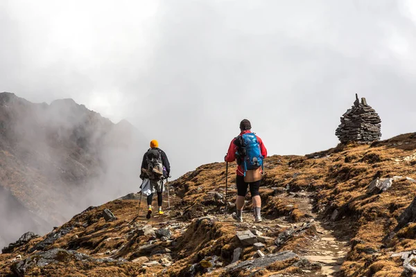 Dois caminhantes caminhando na encosta da montanha em direção a torres de pedra — Fotografia de Stock